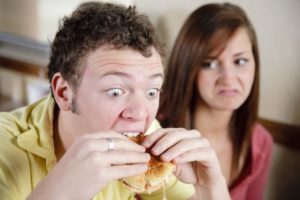 man eating burger, girl pissed
