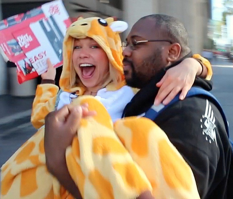 GiGi getting carried by a stranger in a giraffe costume